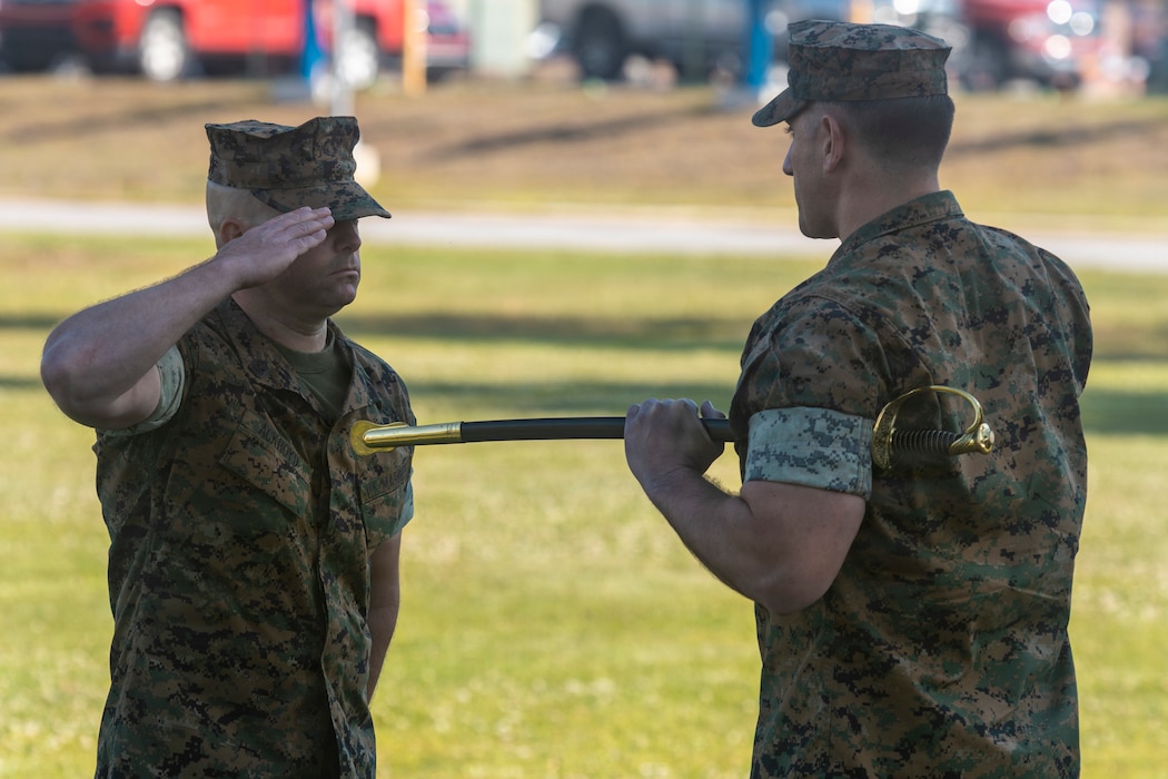 U.S. Marine Corps Sgt. Maj. Justin Ackroyd, left, from Ohio, the incoming command senior enlisted leader of Marine Wing Headquarters Squadron (MWHS) 2, 2nd Marine Aircraft Wing, receives the sword of office from Lt. Col. Keenan Chirhart, right, from Alaska, the commanding officer of  MWHS-2 during a relief and appointment ceremony at Marine Corps Air Station Cherry Point on April 23, 2026. The ceremony represented the transfer of authority, accountability and leadership from Sgt. Maj. Kevin Tucei, from Mississippi, the outgoing command senior enlisted leader of MWHS-2, to Ackroyd. (U.S. Marine Corps photo by Staff Sgt. Maximiliano Rosas)
