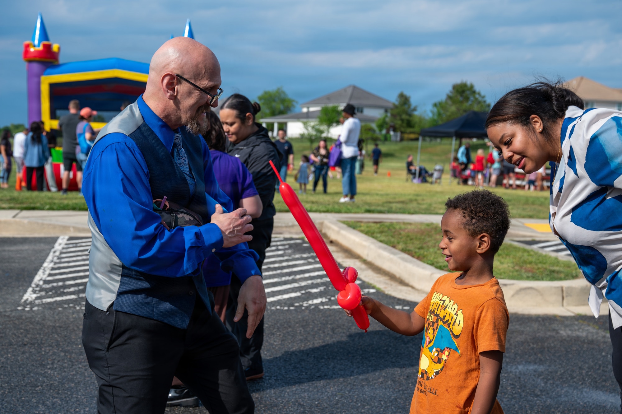 Mark Cleveland, left, 11th Wing Resident Advocate, gives a balloon animal to Khortni Hall, right, and her child at Spring Fest on Joint Base Anacostia-Bolling, Washington, D.C., April 24, 2026. The 11th Force Support Squadron hosted the event in celebration of the Month of the Military Child. (U.S. Air Force photo by Airman 1st Class Arlene Carrara)