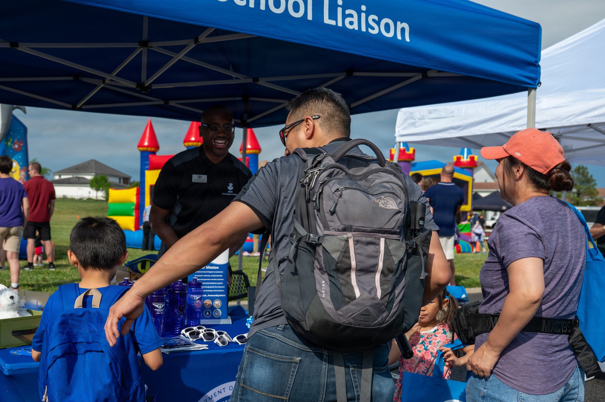 Alonso Hay, center facing camera, Joint Base Anacostia-Bolling school liaison with the 11th Force Support Squadron, provides information to military families at Spring Fest on JBAB, Washington, D.C., April 24, 2026. The 11th Force Support Squadron hosted the event in celebration of the Month of the Military Child. (U.S. Air Force photo by Airman 1st Class Arlene Carrara)