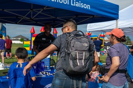 Alonso Hay, center facing camera, Joint Base Anacostia-Bolling school liaison with the 11th Force Support Squadron, provides information to military families at Spring Fest on JBAB, Washington, D.C., April 24, 2026. The 11th Force Support Squadron hosted the event in celebration of the Month of the Military Child. (U.S. Air Force photo by Airman 1st Class Arlene Carrara)