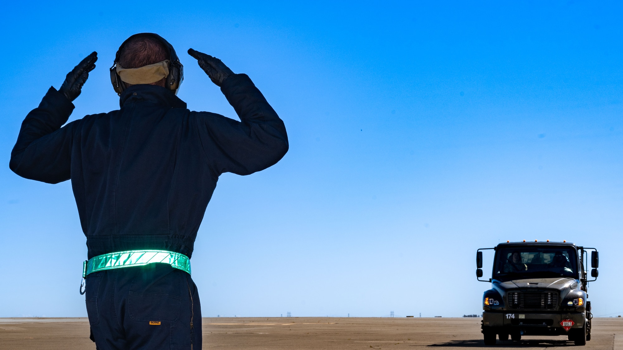A U.S. Airmen ground guides a fuel truck on the flight line at Travis Air Force Base.