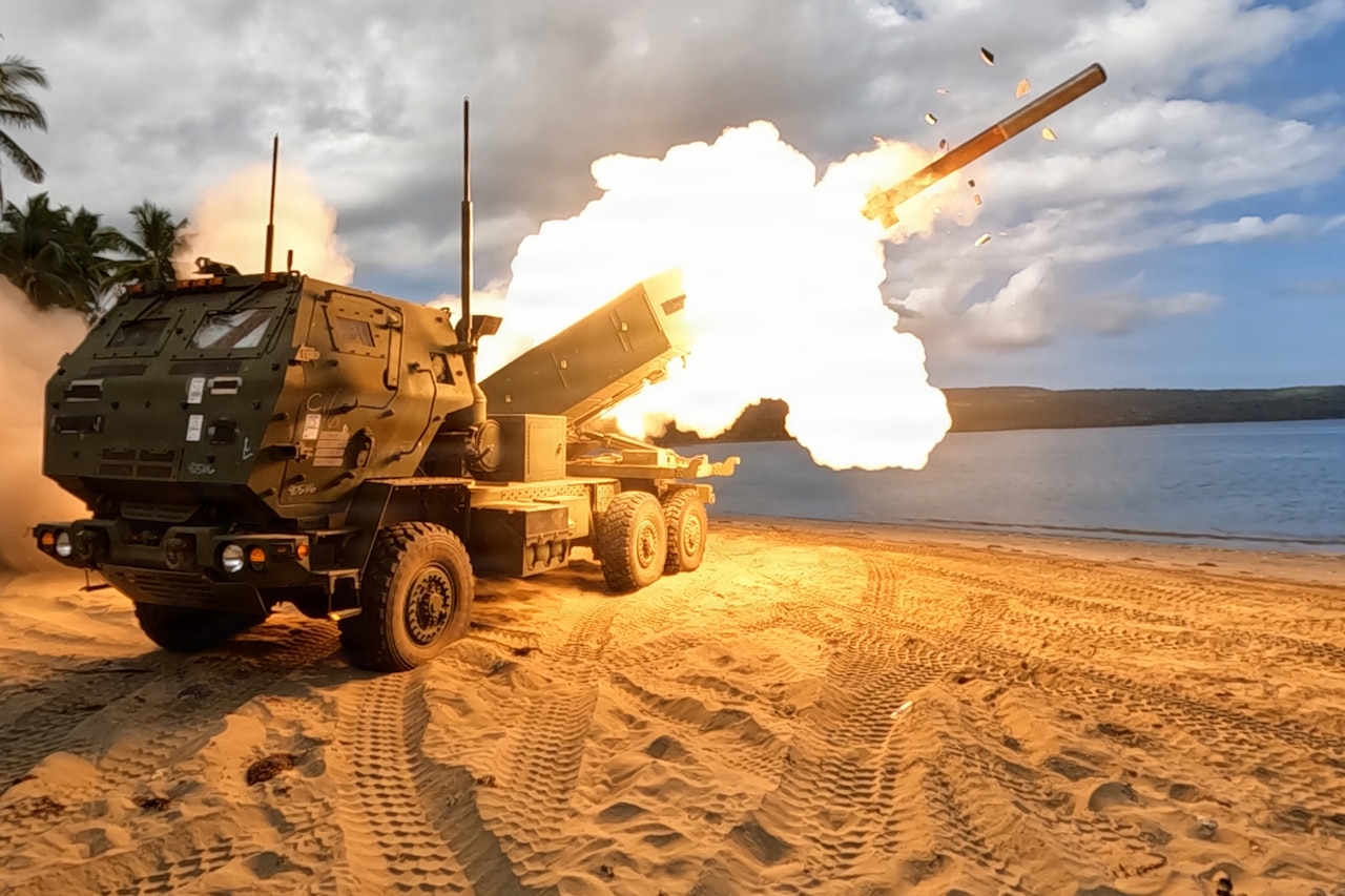A military vehicle parked on a tropical beach launches a rocket.