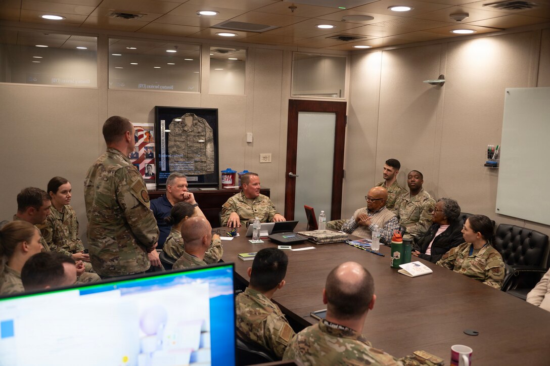 A group of people sit around a conference table conversing.