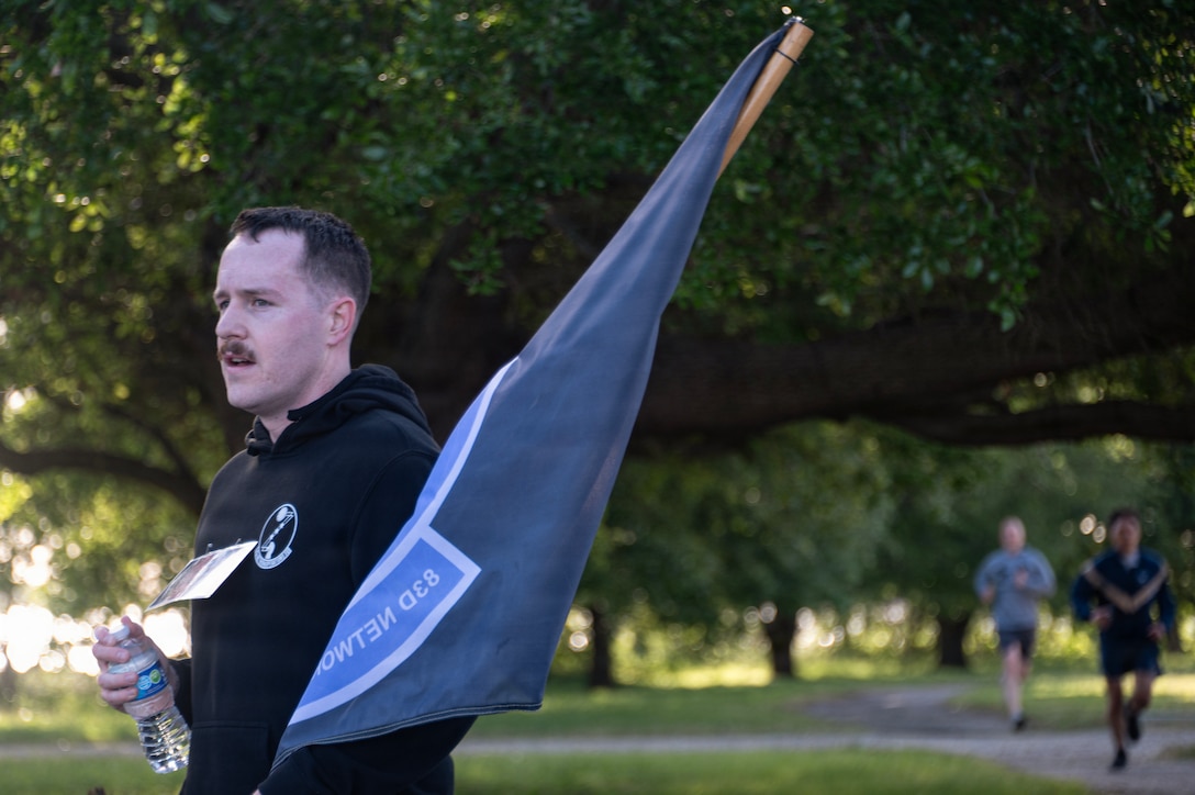 A man holds a blue flag outdoors during an organized memorial event.