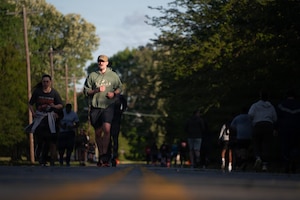 Air Force service members run along a open roadway during an organized memorial event.