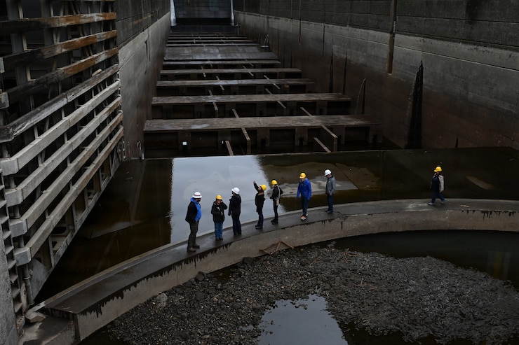 Eight individuals wearing hard hats standing inside of a drained navigation lock.