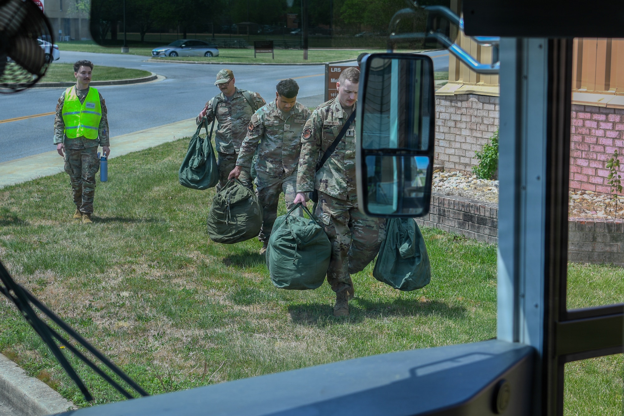 Airmen going towards a bus with luggage.