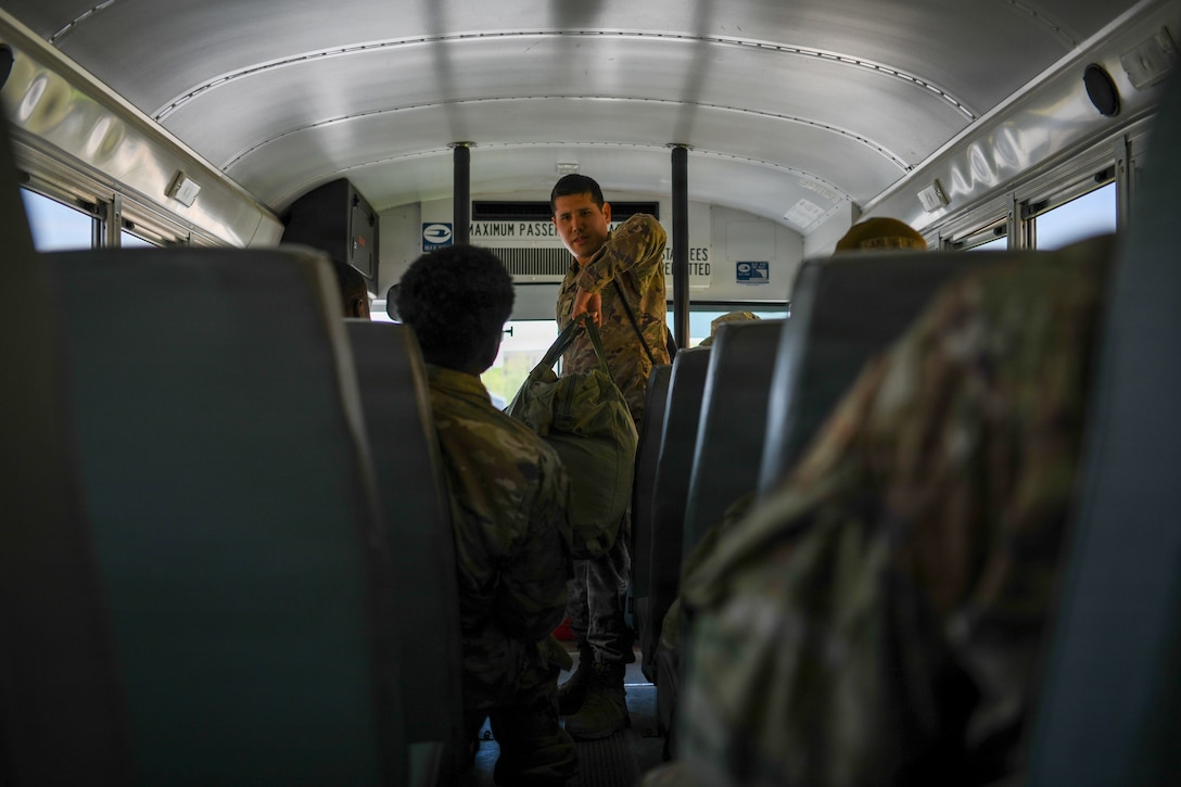 Airmen on a bus with luggage.