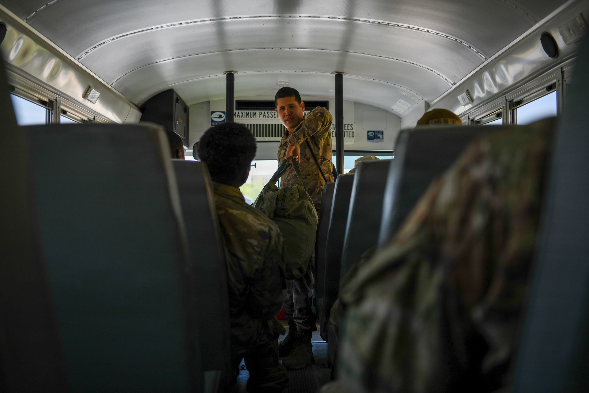 Airmen on a bus with luggage.