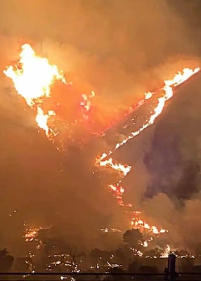 A view of a wildfire on hills at night.