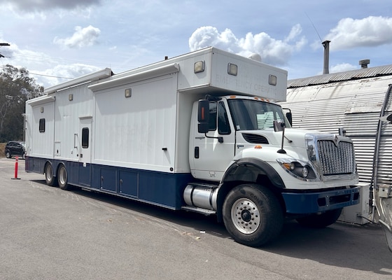A large white command vehicle sits outside.