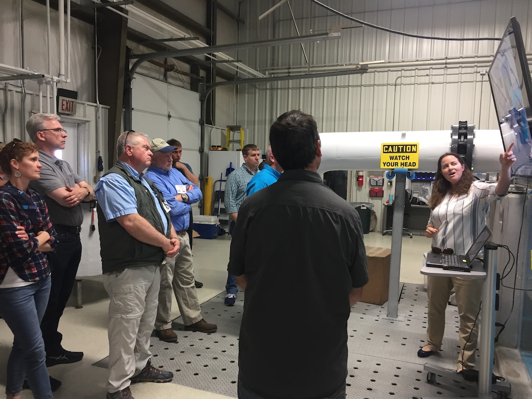 Staff members briefing group of visitors indoors at project facility