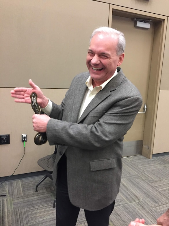 Man in business attire gestures while presenting to audience in conference room