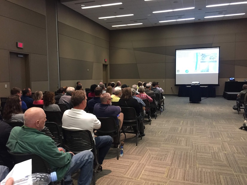 Audience members seated in conference room watching presentation screen