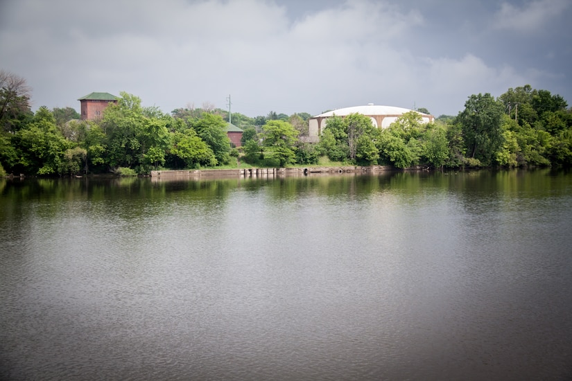 Grand River with urban development and vegetation along banks under partly cloudy sky