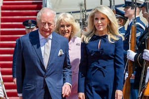 Their Majesties of the United Kingdom of Great Britain and Northern Ireland, King Charles III and Queen Camilla, walk down a red carpet with the Chief of Protocol of the U.S. Monica Crowley.