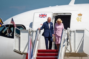 Their Majesties of the United Kingdom of Great Britain and Northern Ireland, King Charles III and Queen Camilla, descend the stairs of a United Kingdom aircraft.