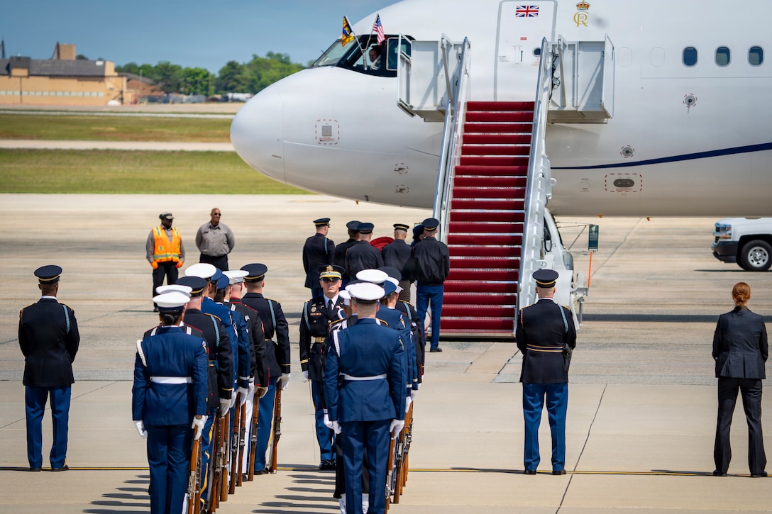 U.S. service members with an armed forces full honor cordon and Department of War security personnel stand in front of a United Kingdom aircraft.