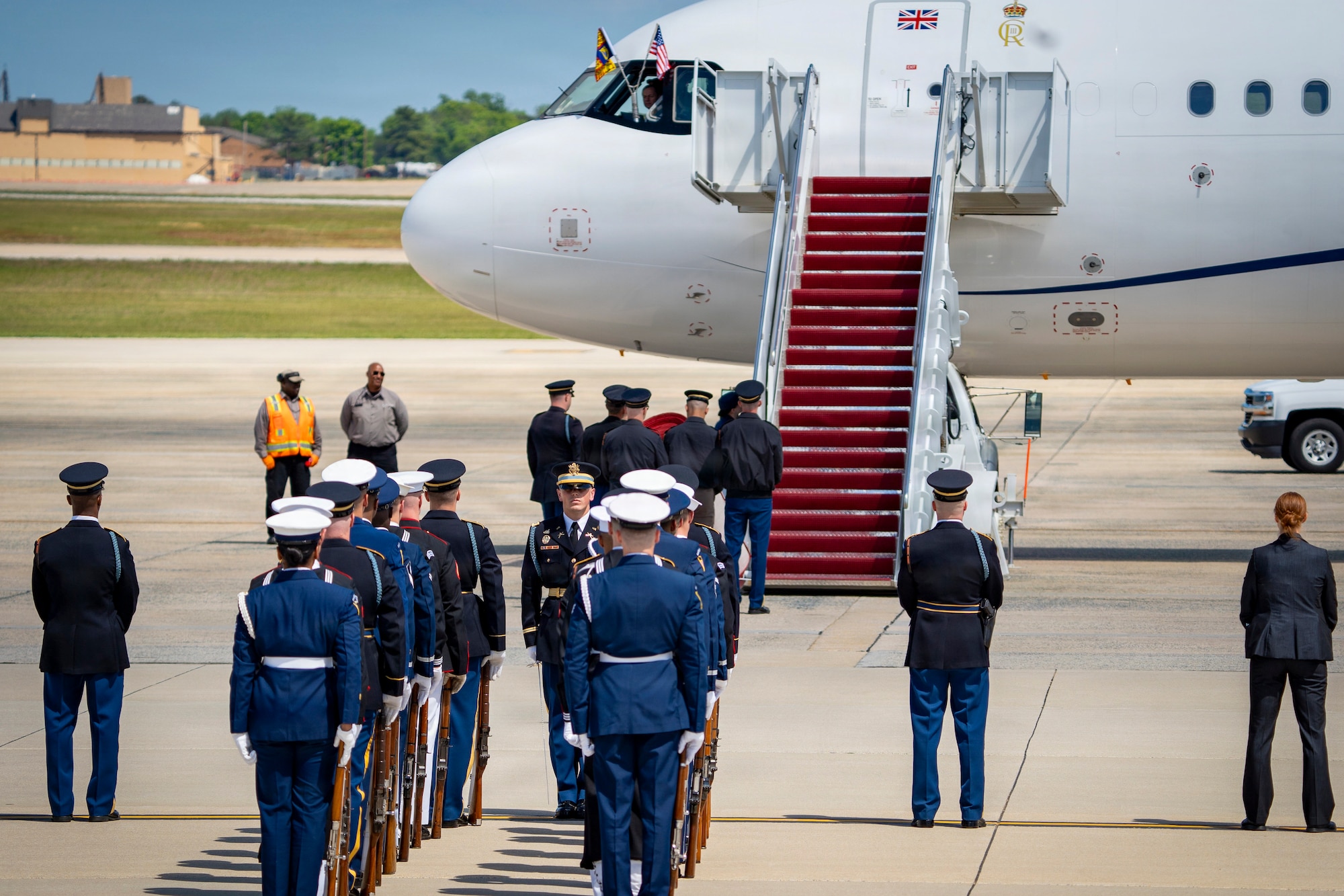 U.S. service members with an armed forces full honor cordon and Department of War security personnel stand in front of a United Kingdom aircraft.