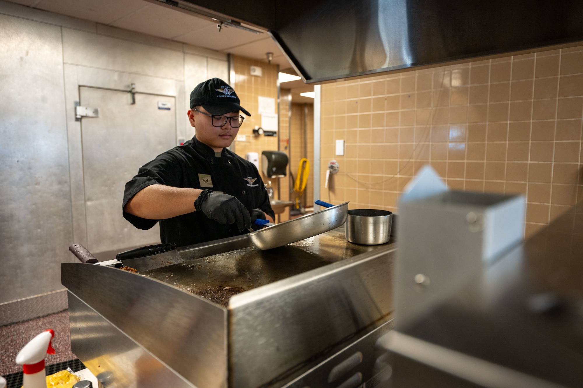 A uniformed man cooks food.