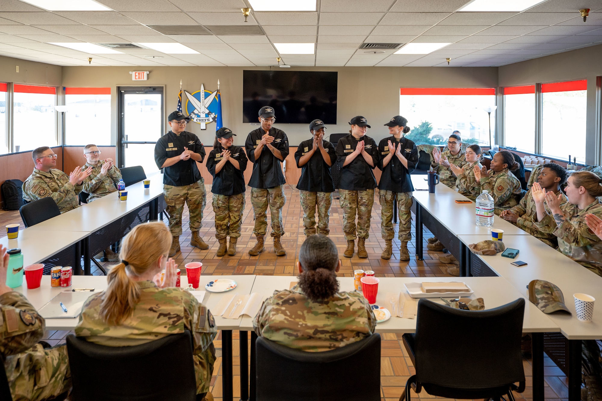 A group of uniformed personnel claps during a training event.