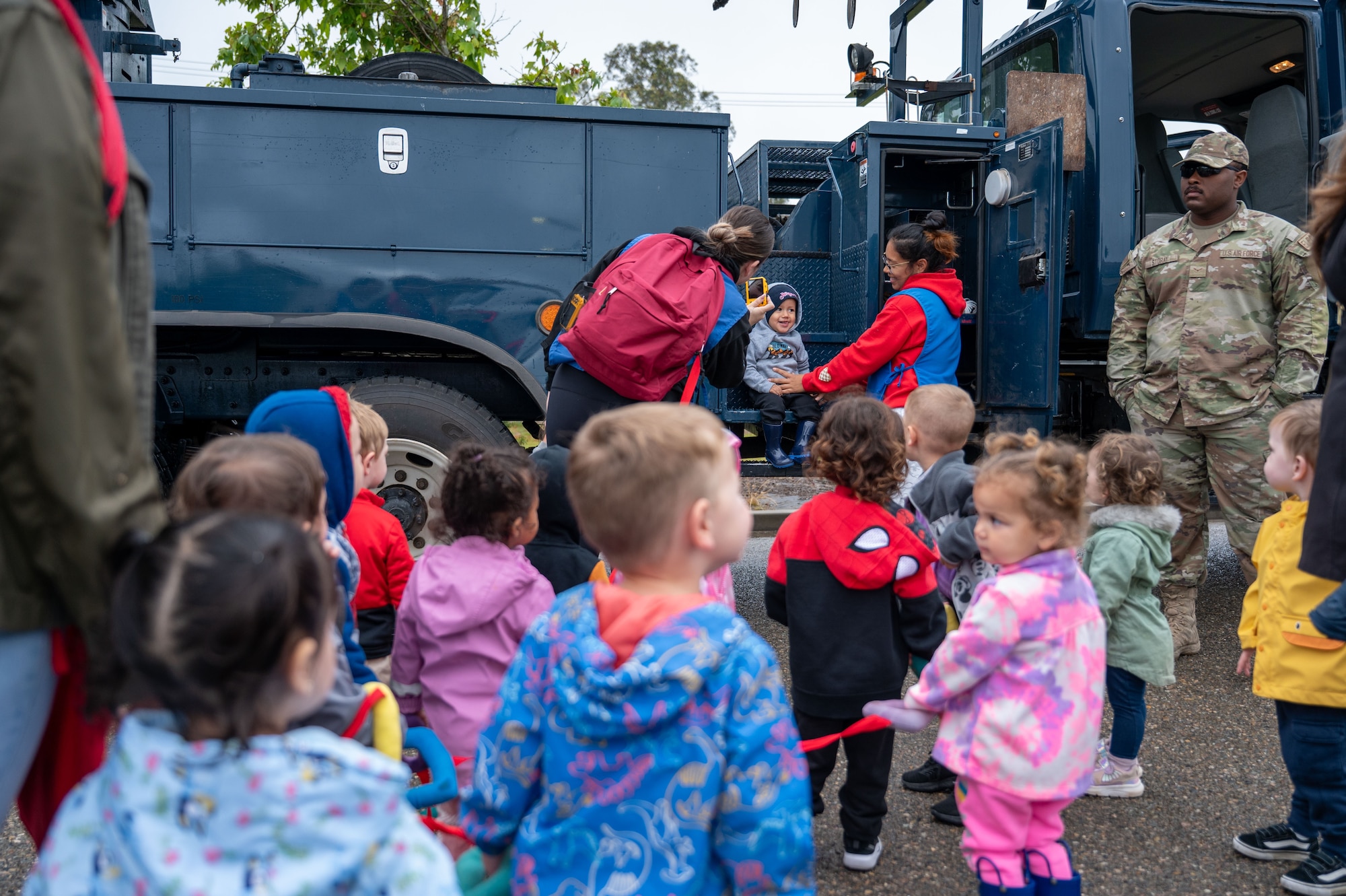 a group of children stand in front of a construction vehicle