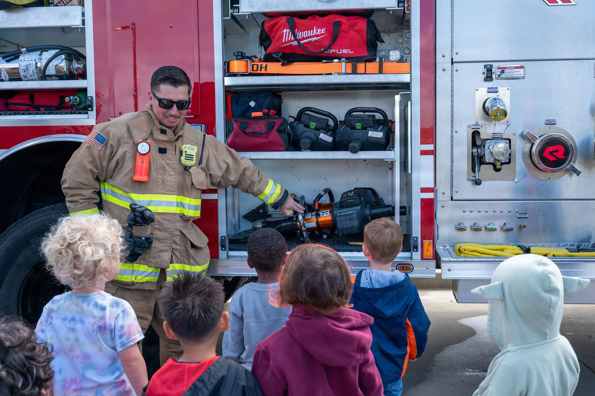 a firefighter presents tools to a group of children