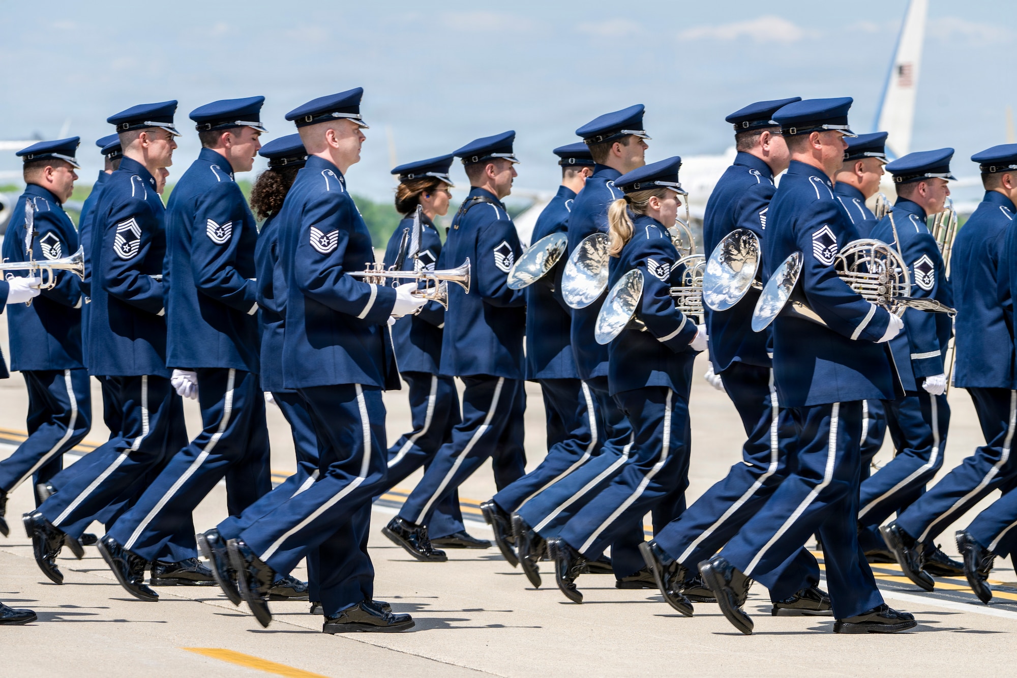 U.S. Airmen with the Air Force Band march across the flight line during a military arrival ceremony for Their Majesties of the United Kingdom of Great Britain and Northern Ireland.