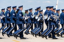 U.S. Airmen with the Air Force Band march across the flight line during a military arrival ceremony for Their Majesties of the United Kingdom of Great Britain and Northern Ireland.