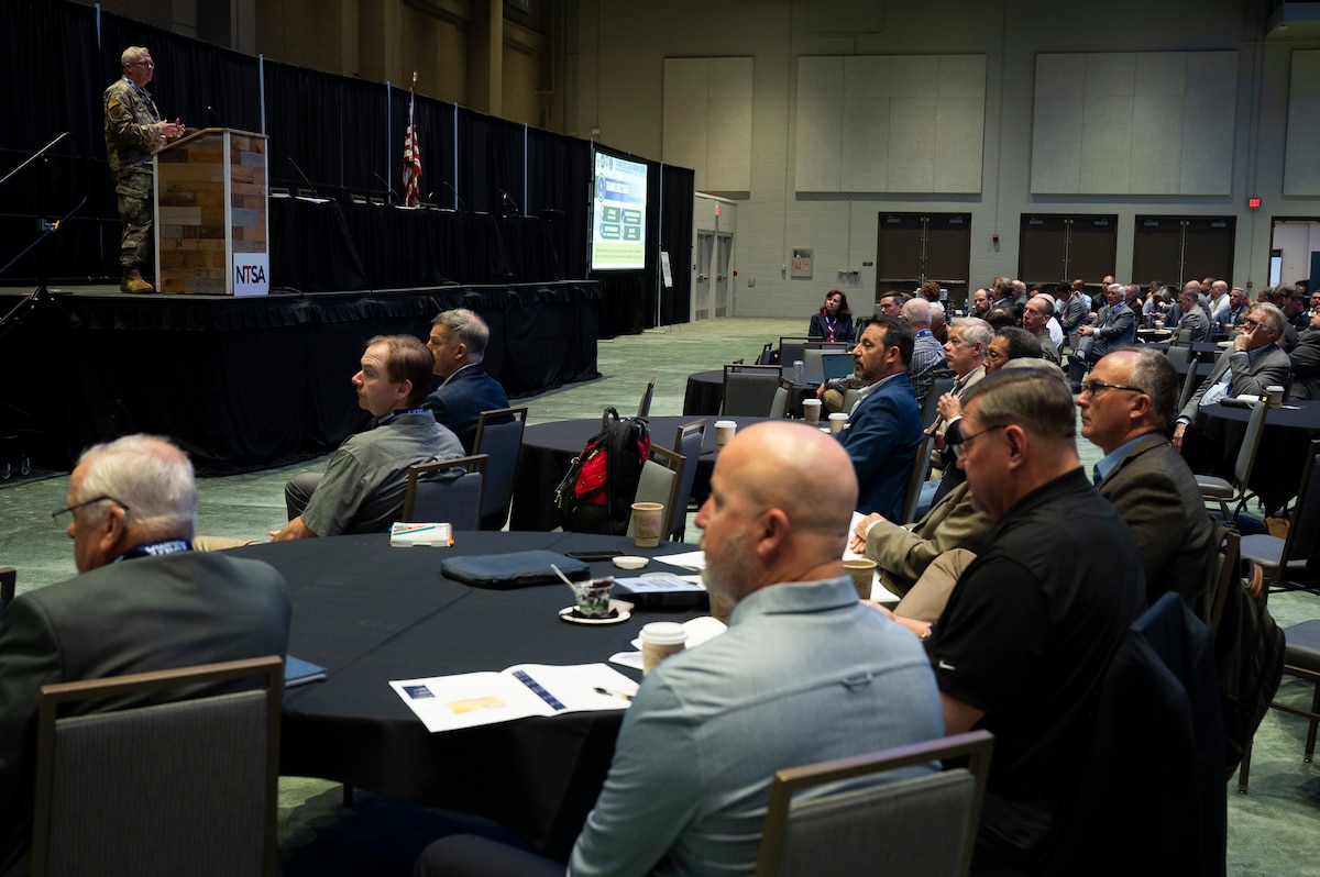 Individuals seated at tables watching convention speakers.