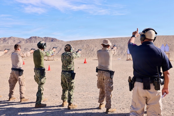 Provost Marshal’s Office Training Sgt. Juan Montero signals Marines and Sailors to begin firing as Lt. j.g. Duane A. Daquioag (center) and Hospital Corpsman 3rd Class Ayden Z. Massey (center left), both assigned to Navy Medicine Readiness and Training Command Twentynine Palms, prepare to engage targets with the M9 service pistol during training at Marine Corps Air Ground Combat Center Twentynine Palms, Calif., March 26, 2026. (U.S. Navy photo by Christopher Jones, NMRTC/NH Twentynine Palms public affairs officer)