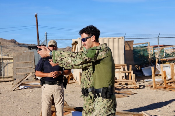 Provost Marshal’s Office Training Sgt. Juan Montero (left) instructs Hospital Corpsman 3rd Class Ayden Z. Massey (right) and Lt. j.g. Duane A. Daquioag, both assigned to Navy Medicine Readiness and Training Command Twentynine Palms, on proper firing and reloading techniques with the M9 service pistol during training at Marine Corps Air Ground Combat Center Twentynine Palms, Calif., March 26, 2026. (U.S. Navy photo by Christopher Jones, NMRTC/NH Twentynine Palms public affairs officer)