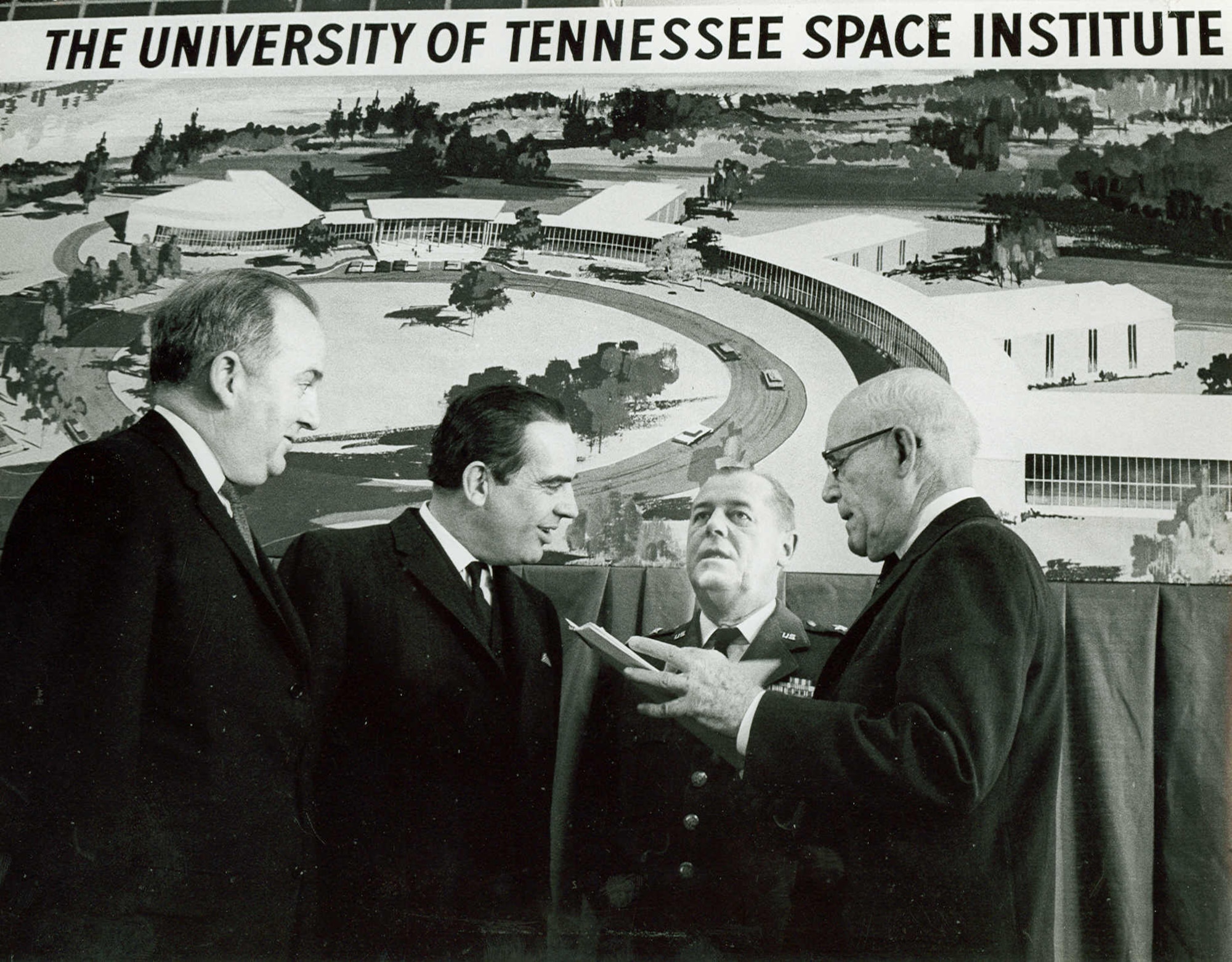U.S. Department of Health, Education and Welfare Capt. Richard Lyle, right, presents a land deed for the University of Tennessee Space Institute to Tennessee Gov. Frank Clement, second from left, during a Jan. 29, 1964, ceremony at Arnold Engineering Development Center. The first UTSI classes were held Sept. 24, 1964, at AEDC in offices provided by the Air Force as UTSI was constructed. In the years leading up to the establishment of UTSI, a program was in place through which the University of Tennessee would award graduate degrees to engineers at AEDC. Also pictured are Arnold Research Organization President R.M. Williams, left, and then-AEDC Commander Maj. Gen. William L. Rogers. (U.S. Air Force photo)