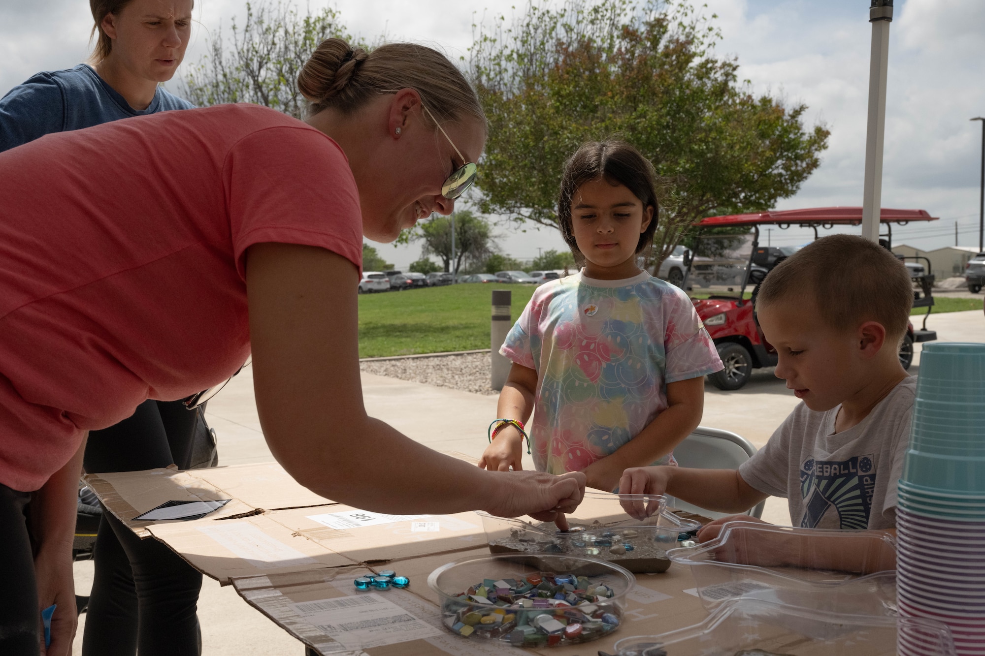 U.S. Air Force Tech. Sgt. Cari Gamez, 47th Flying Training Wing command chief executive assistant, assists a child in creating a decorative stepping stone at Laughlin Air Force Base, Texas, April 22, 2026. Gamez assisted the Laughlin Warrior Action Team during the Rooted in Resilience event for military families. (U.S. Air Force photo by Airman 1st Class Darryl Keith)