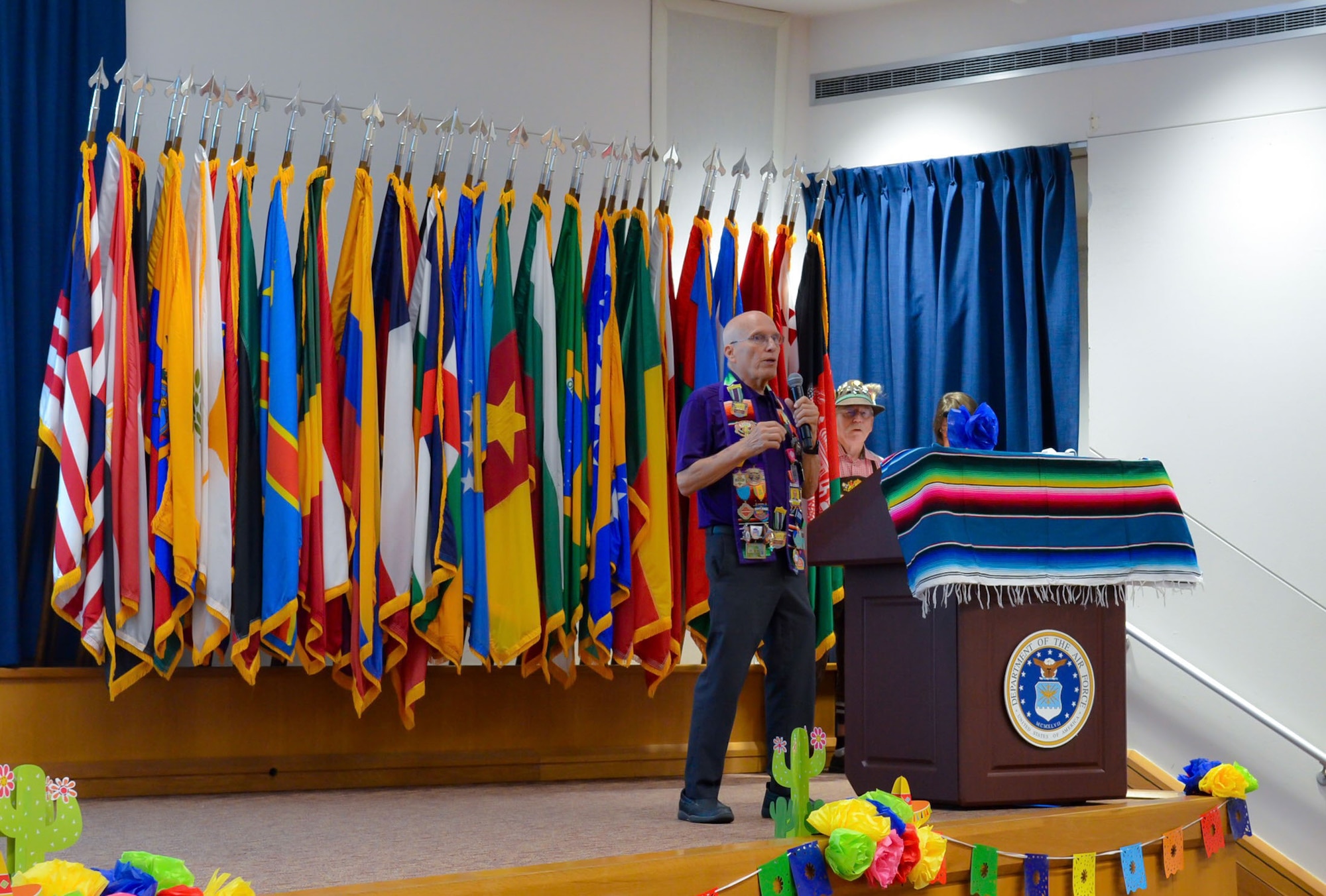Lewis Vetter, President of the Conservation Society of San Antonio, speaks during the Fiesta Showcase at the Defense Language Institute English Language Center in San Antonio, Texas, April 15, 2026.  Vetter shared the organization’s role in preserving San Antonio’s history and supporting the community during the event. DLIELC is known as the “Gateway to America,” and builds security cooperation through English language training and cultural immersion for international military partners and pre-basic combat trainees in the U.S. Army and Coast Guard. (U.S. Air Force photo by Agnes Koterba)