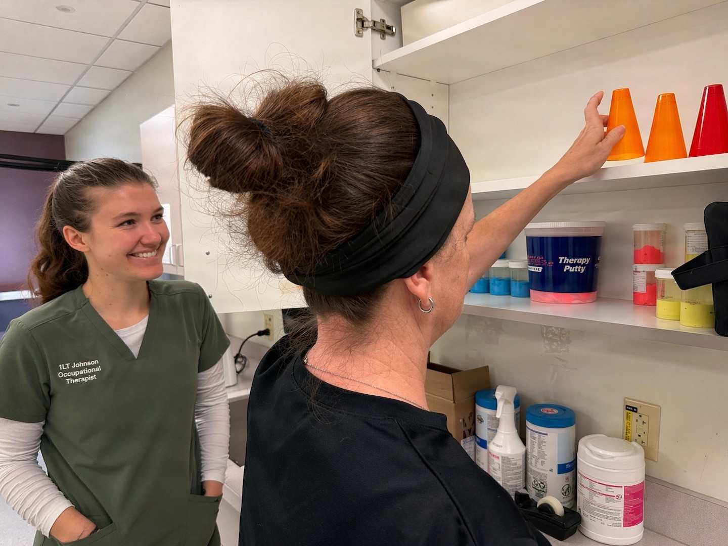 Occupational Therapist observes patient performing exercise.