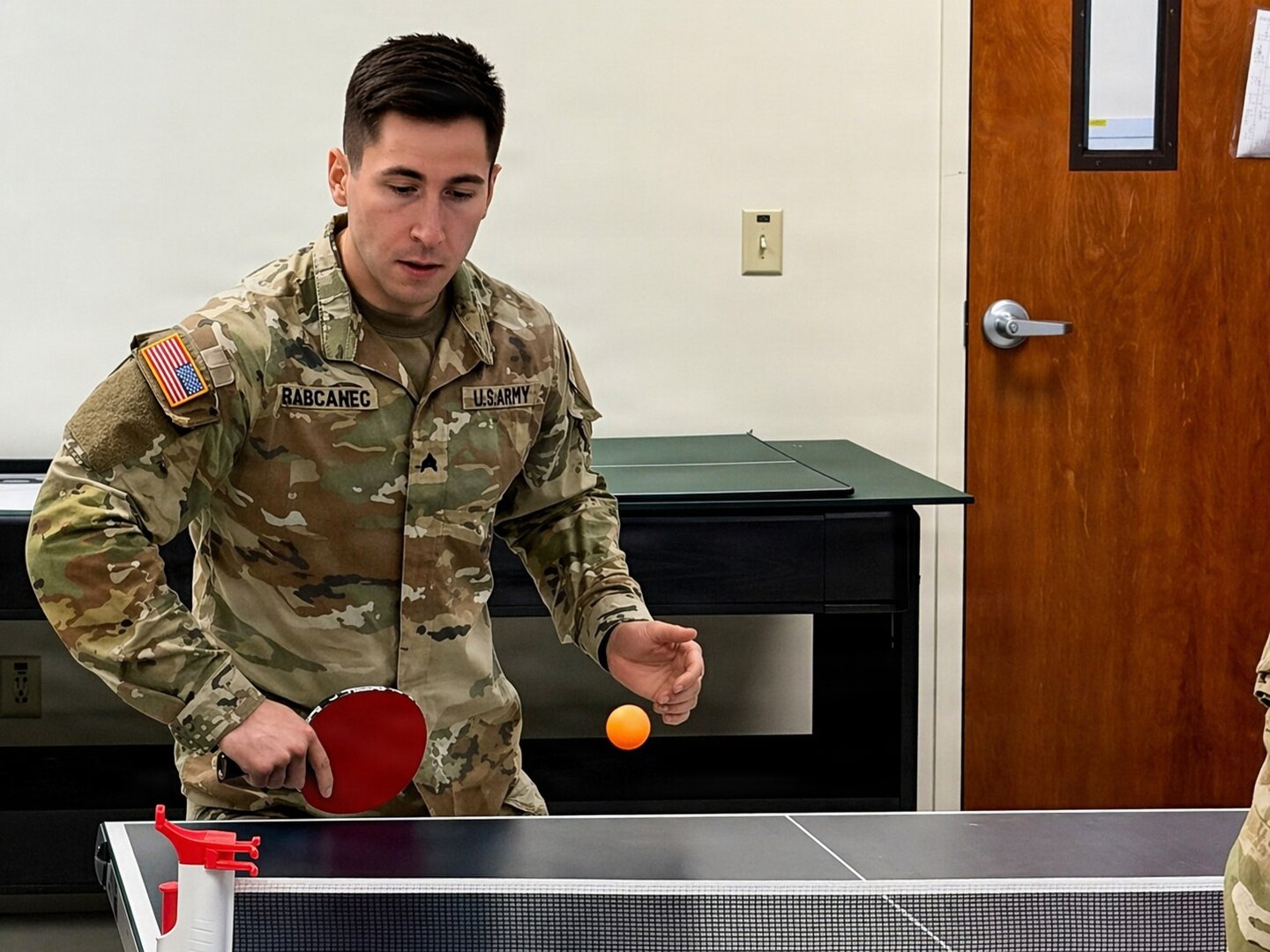 Soldier in uniform plays ping pong.