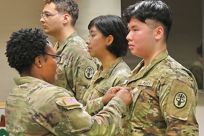 Military leader pins new rank on young Soldier during a promotion ceremony.