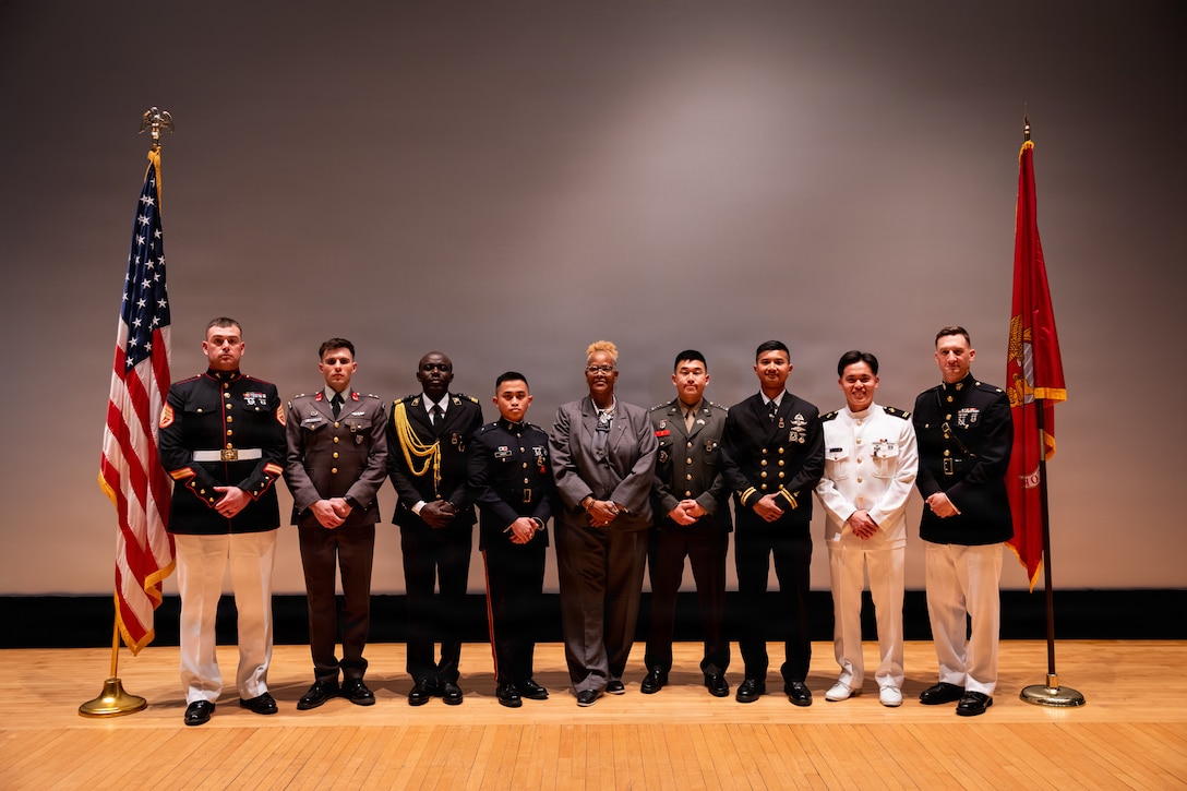 U.S. Marines and foreign military graduates with Basic Officer Course 5-25, Company E, The Basic School, Training Command, pose for a photo after a graduation ceremony at Marine Corps Base Quantico, Virginia, March 13, 2026. TBS trains and educates newly commissioned or appointed officers in the high standards of professional knowledge, esprit de corps, and leadership to prepare them for duty as company-grade officers. (U.S. Marine Corps photo by Cpl. Joshua Barker)