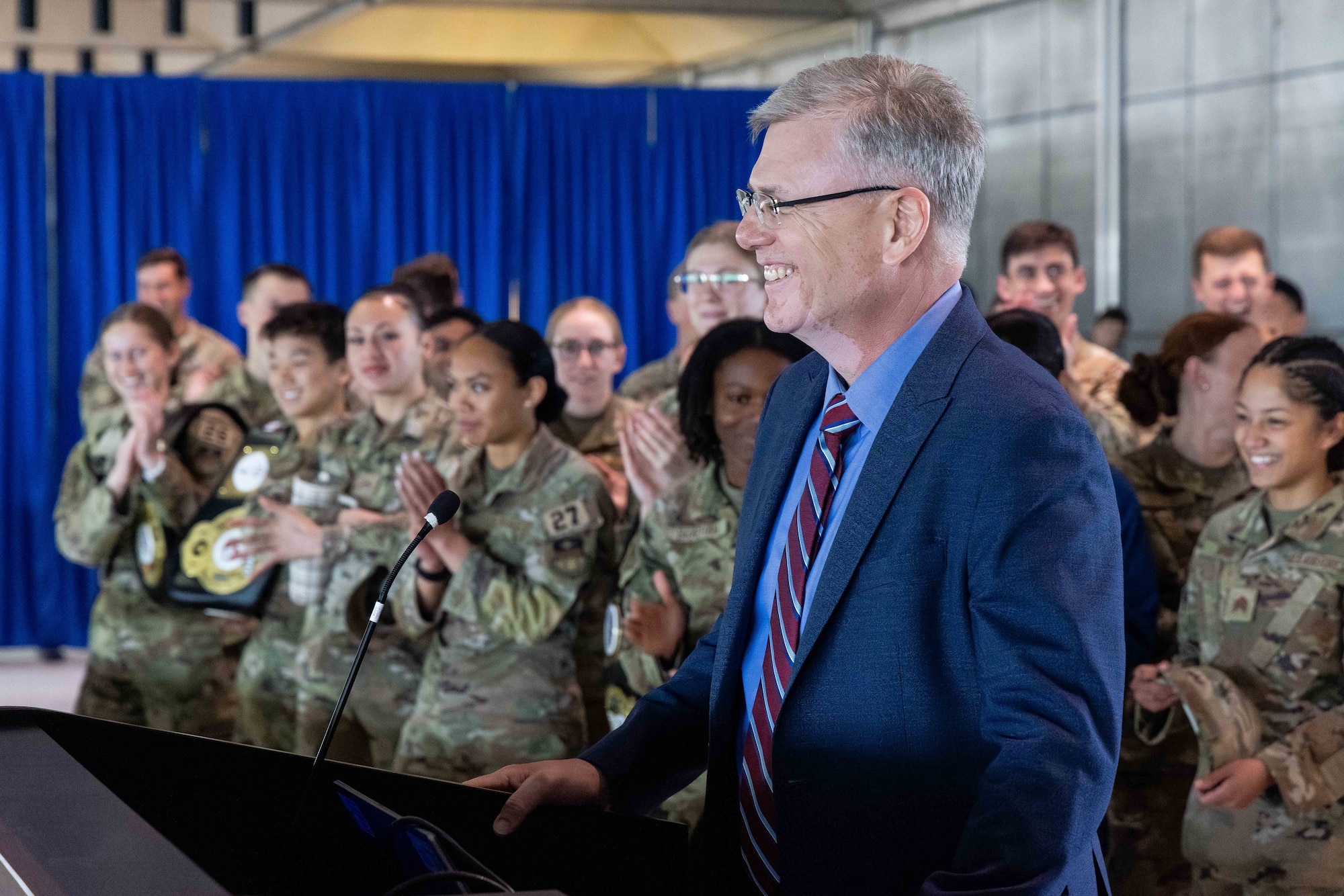 The Secretary of the Air Force stands in front of a podium with Cadets clapping in the background.