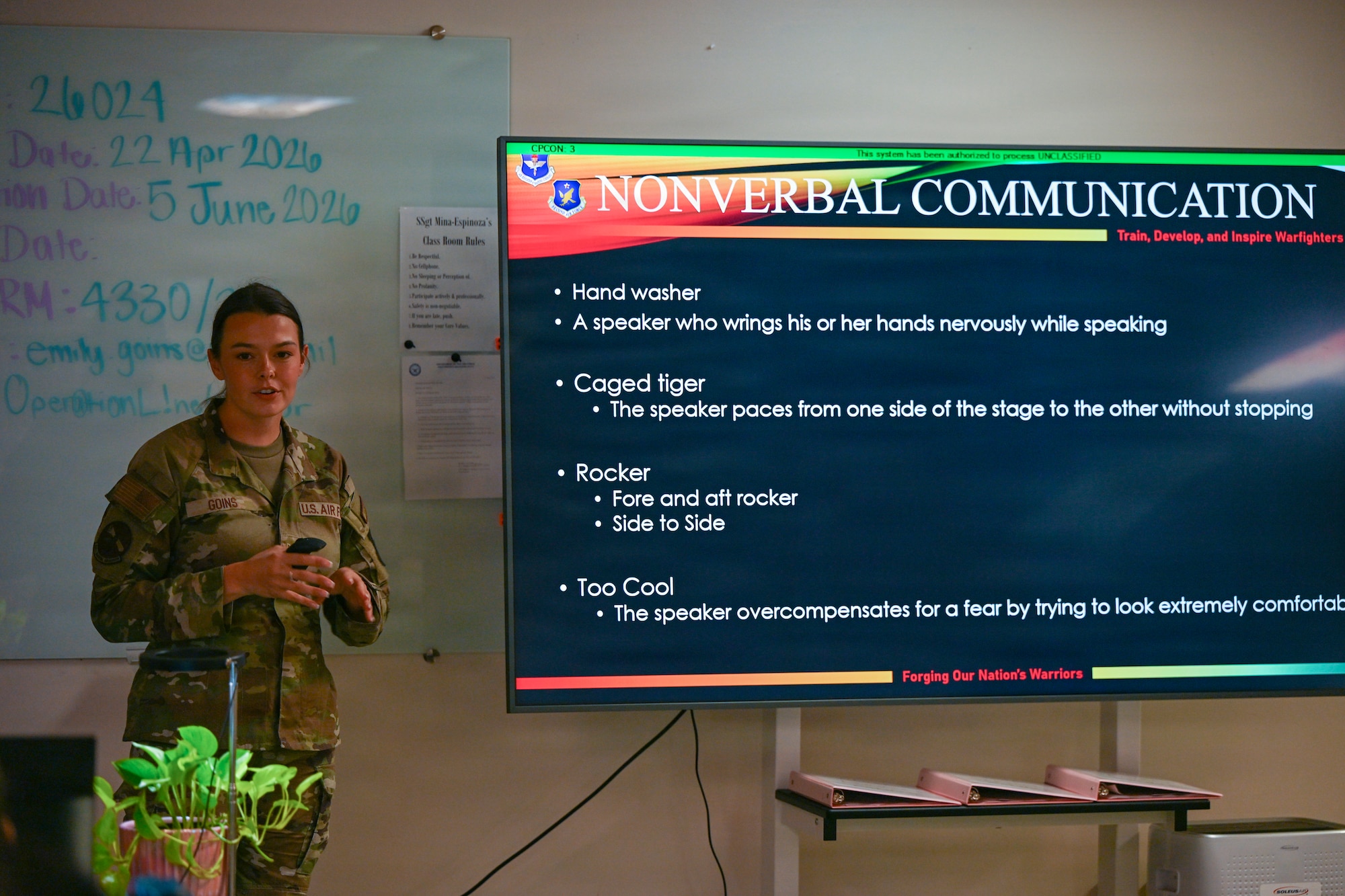 A person in military uniform is displayed in a classroom.