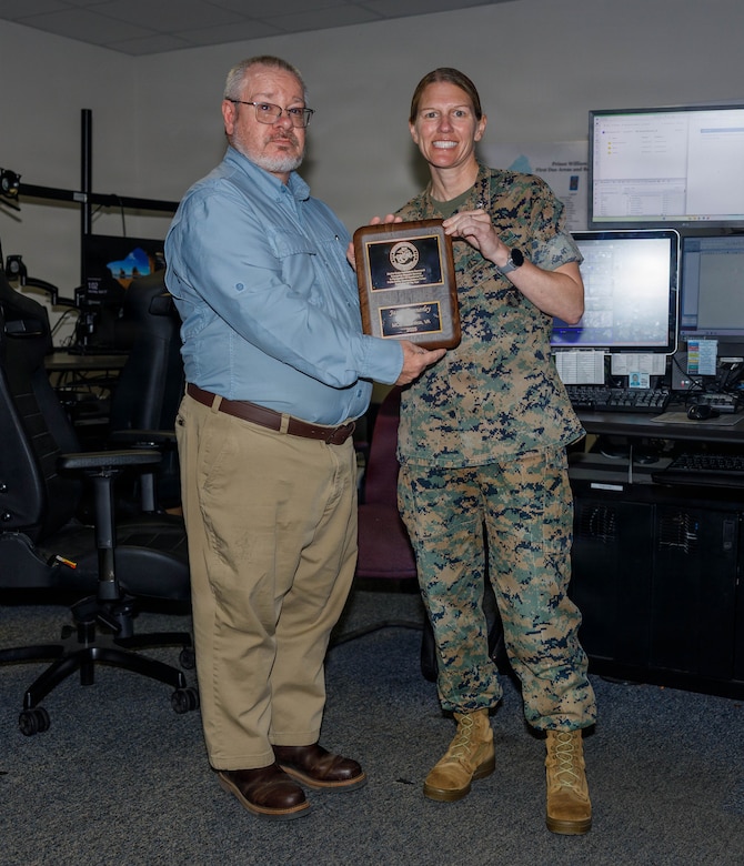 Jason Connerley, the dispatch supervisor of the Quantico Emergency Communication Center, left, and U.S. Marine Corps Col. Jenny Colegate, the commanding officer of Marine Corps Base Quantico, pose for a photo during Connerley’s award ceremony at the ECC on MCB Quantico, Virginia, April 27, 2026. The Public Safety Communications Center Supervisor of the Year Award is given for professional achievement and dedication, something that Connerley demonstrated throughout his time as an important asset of MCB Quantico and the ECC. (U.S. Marine Corps photo by Lance Cpl. Lynsee Avila-Ramirez)