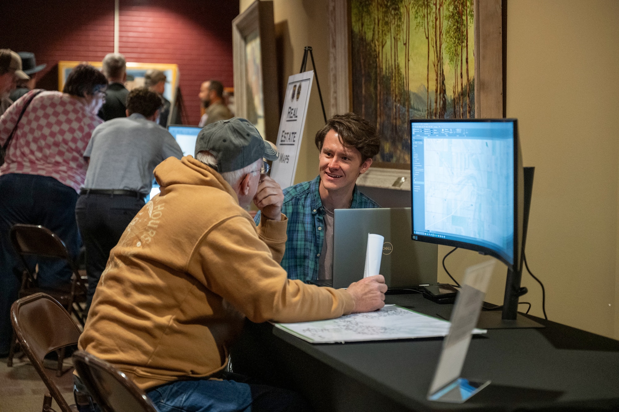 Two men talking while sitting down in front of computers.