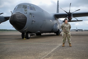 A woman poses for a photo next to a C-130J Super Hercules.