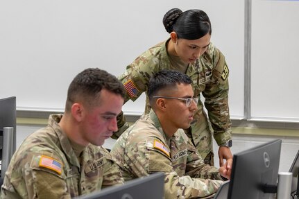 Staff Sgt. Chelsea Samatra, U.S. Army Finance and Comptroller School course developer, right, helps Spc. Erick Bedoya, 15th Finance Battalion financial management technician, center, as he and Cpl. Hunter Pressley, 15th FIBN financial management technician, left, take part in a two-hour essay writing exercise at Fort Jackson, S.C., April 21, 2026. Twelve finance and comptroller Soldiers wrote essays as part of the U.S. Army Finance Corps’ annual Finance Soldier of the Year competition. (U.S. Army photo by Mark R. W. Orders-Woempner)
