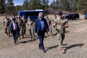 A group of Cadets and men in suits walk away from a bus.