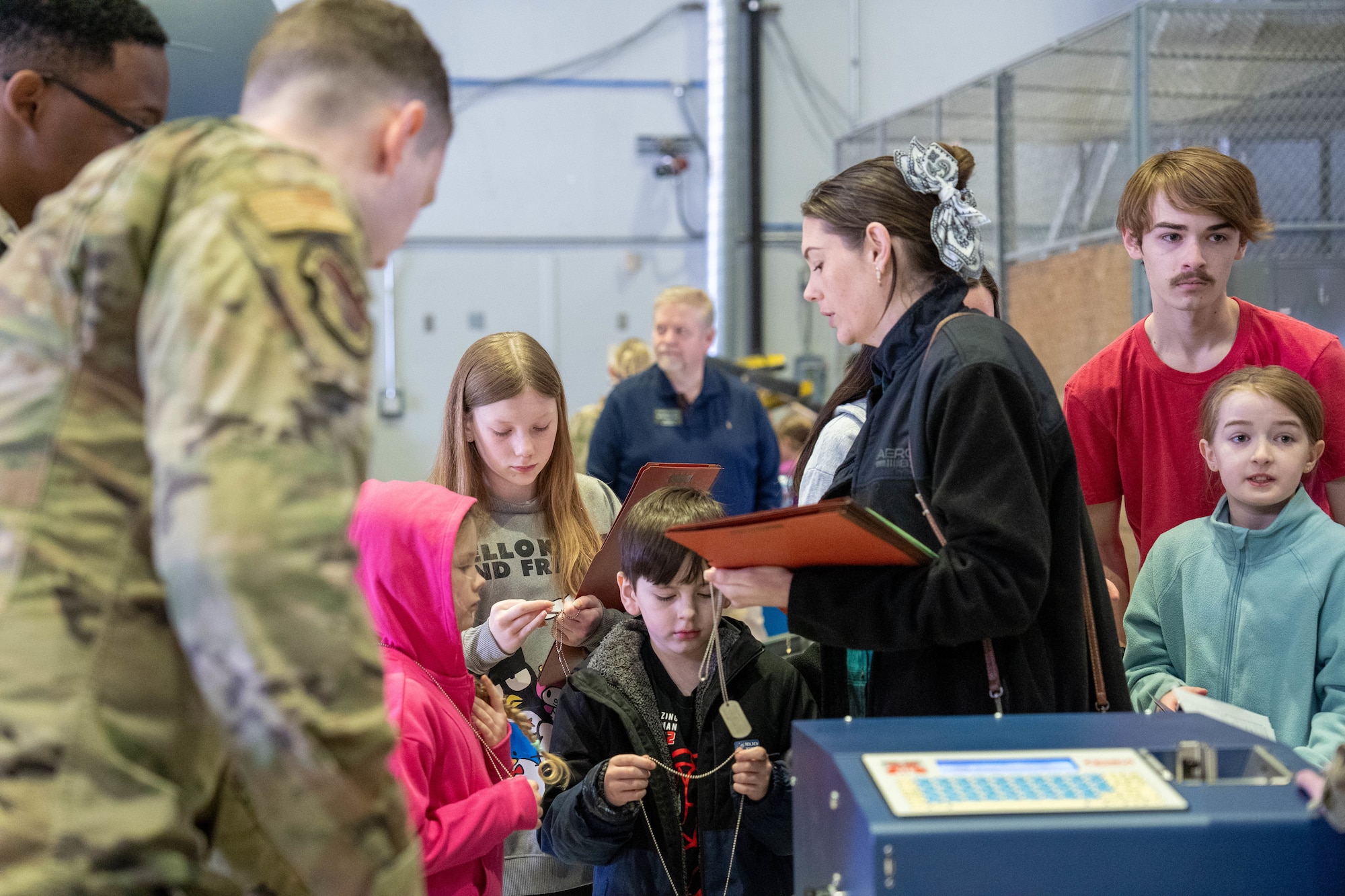 Children recieve their dog tags during a family deployment line on Joint Base Elmendorf-Richardson, Alaska, April 25, 2026. During the morale-boosting event, families were given the opporitunity to learn about pre-deployment processes such as medical clearance, weapons training and safety equipment issue. (U.S. Air Force photo by Airman 1st Class Keola Vischi)