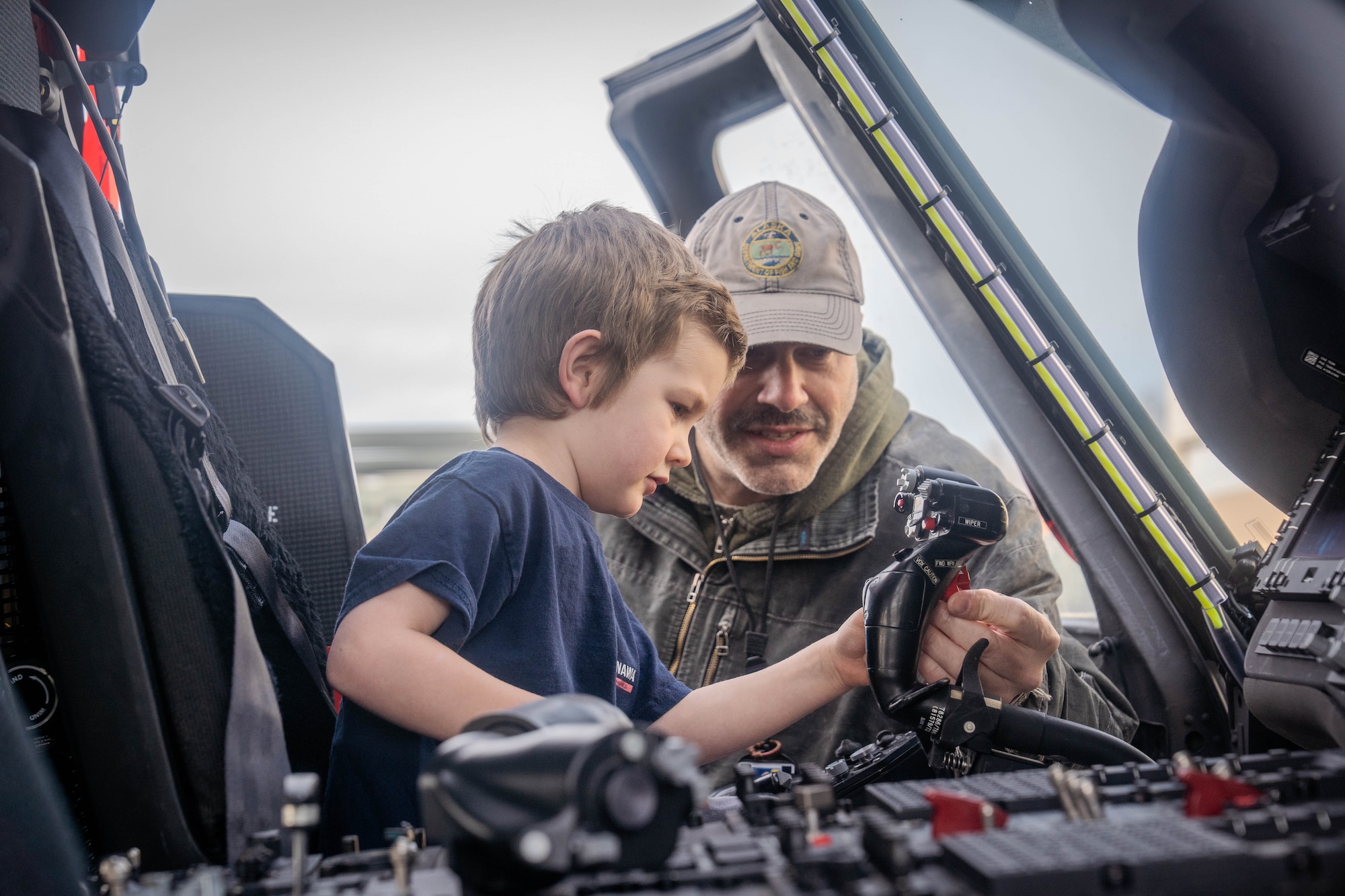 Families on Joint Base Elmendorf-Richardson sit inside of a cockpit of a U.S. Air Force HH-60 Pavehawk static display during a family deployment line on JBER, Alaska, April 25, 2026. For Month of the Military Child, JBER hosted a family deployment line to boost morale, reflecting procedures in a real-world deployment scenario. Activities at the event included safety equipment issue, a mock weapon qualification and a showcasing of aircraft on JBER. (U.S. Air Force photo by Airman 1st Class Keola Vischi)