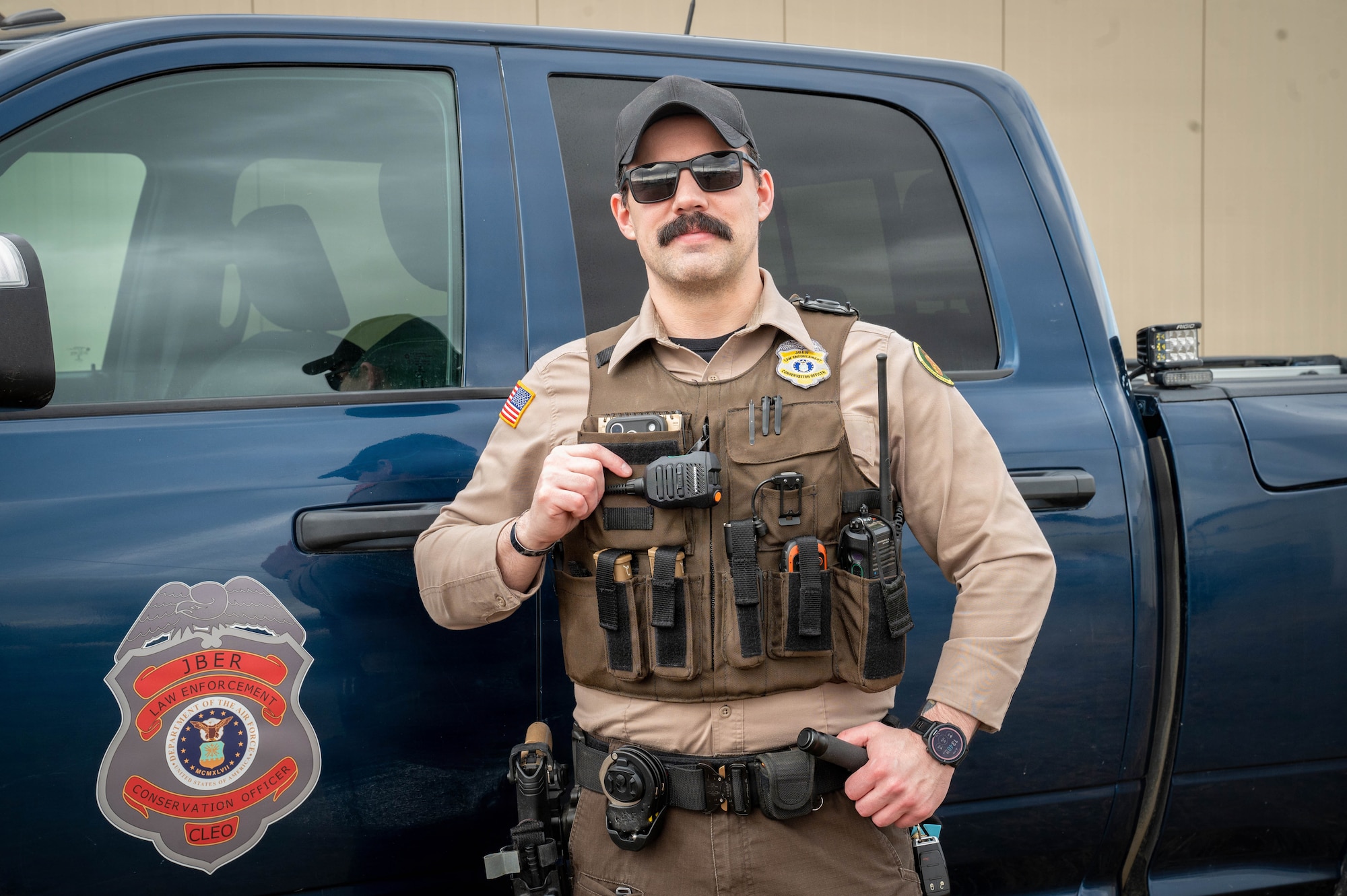 Marshall Hickman, conservation law enforcement officer, stands in front of a Conservation Law Enforcement vehicle displaying the emblem of the organization on Joint Base Elmendorf-Richardson, Alaska, April 27, 2026.