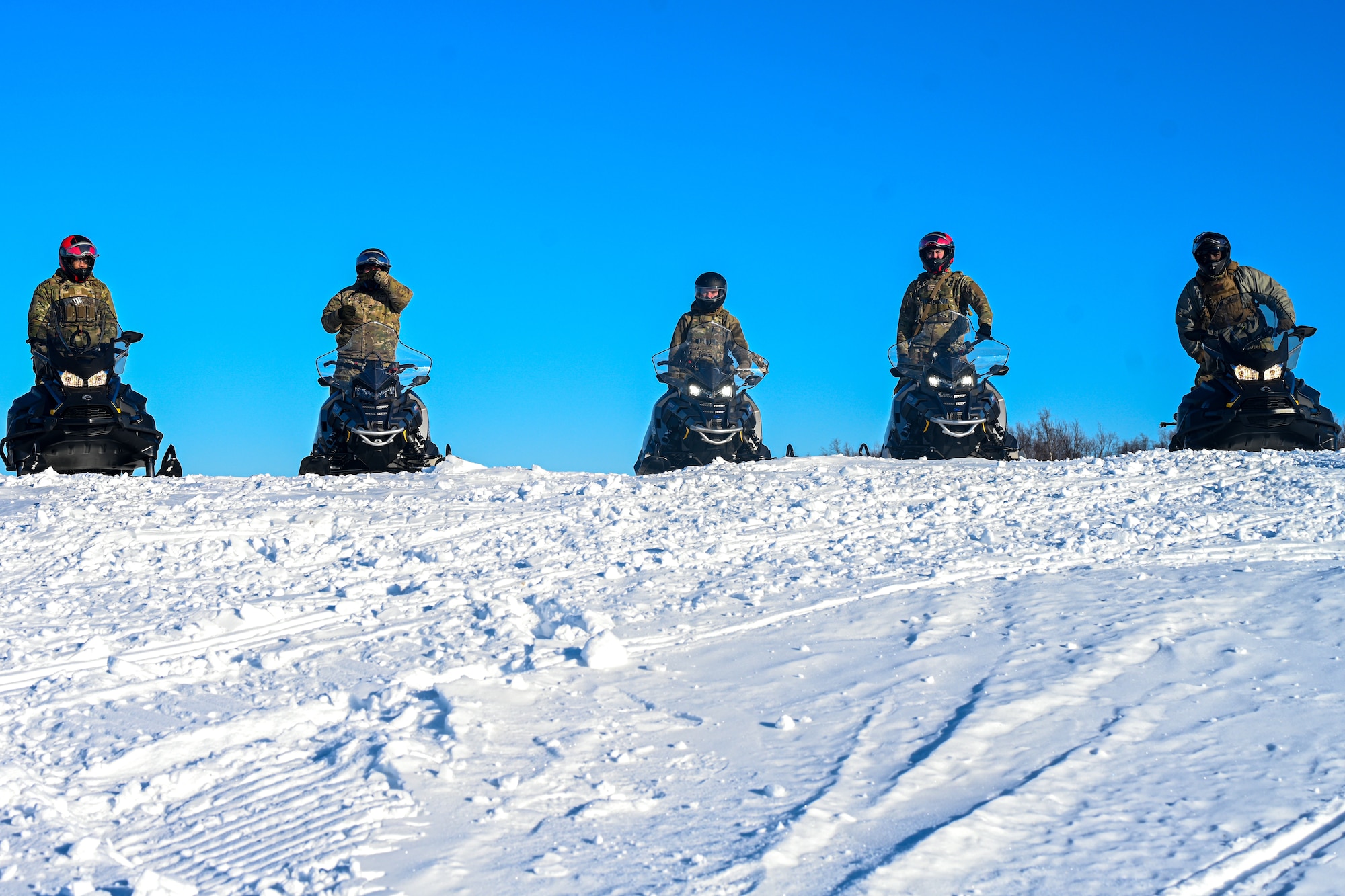 Members of the U.S. Air Force 673d Security Forces Squadron sit on snowmachines during the Arctic Combat Development Course on Joint Base Elmendorf-Richardson, Alaska, March 26, 2026. ACDC is a new course designed and developed to enhance combat capabilities for Airmen in austere arctic environments. (U.S. Air Force photo by Airman 1st Class Eli A. Rose)